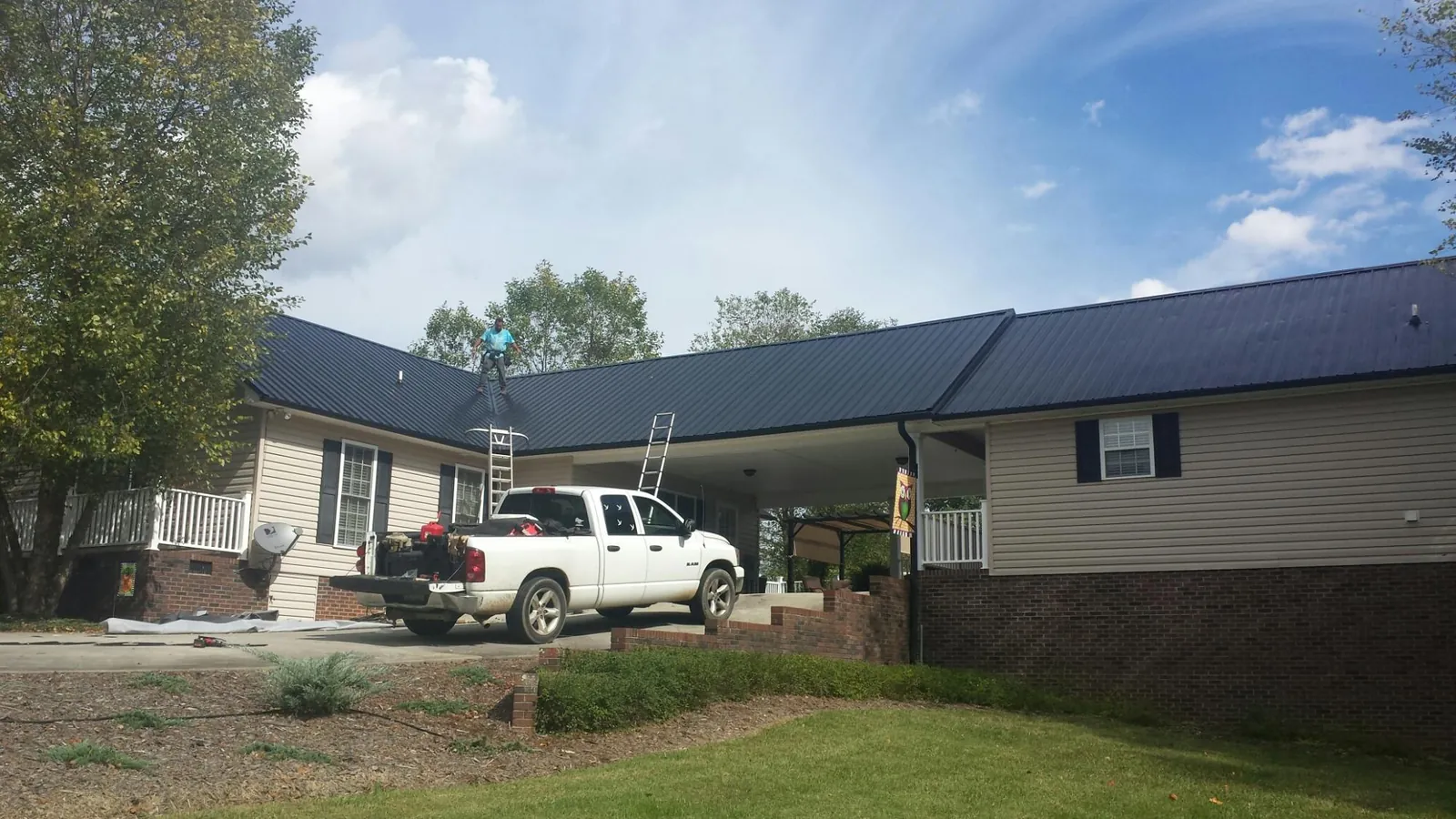 Black metal roof over a home and attached breezeway with ladders set in Yale